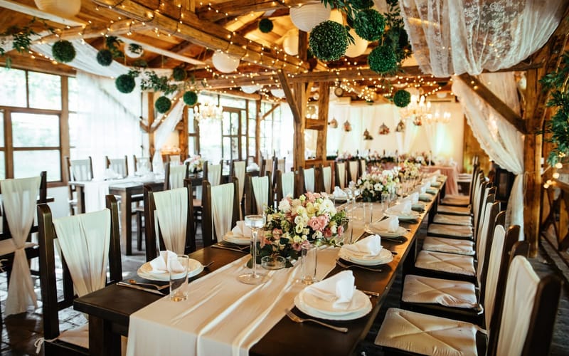 A rustic barn wedding reception set with long tables and hanging lights