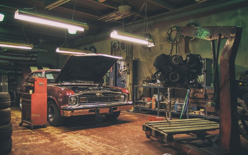 The interior of a car repair shop with an engine on a hoist